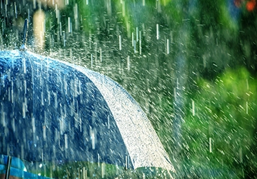Rain pouring on a blue umbrella, illustrating the unpredictable fall weather in Western Washington and the importance of HVAC system preparation.