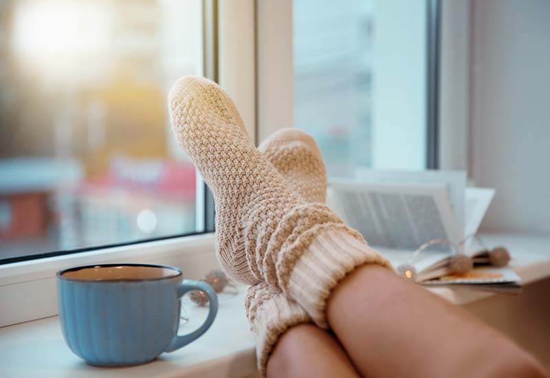 Woman putting feet up on a window sill next to a cup of coffee